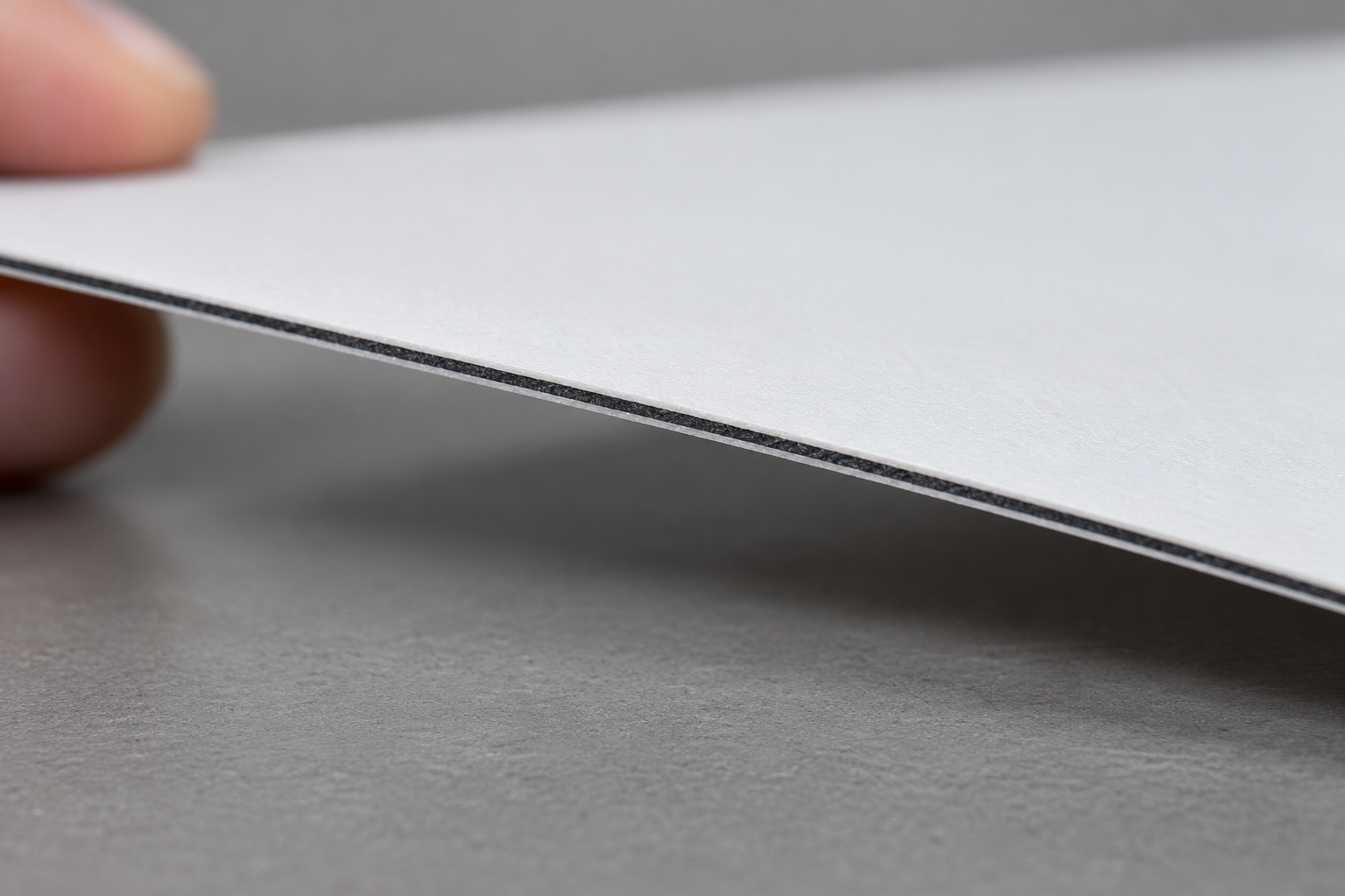 Macro view of a white-faced synthetic sheet edge showing a thin internal dark core